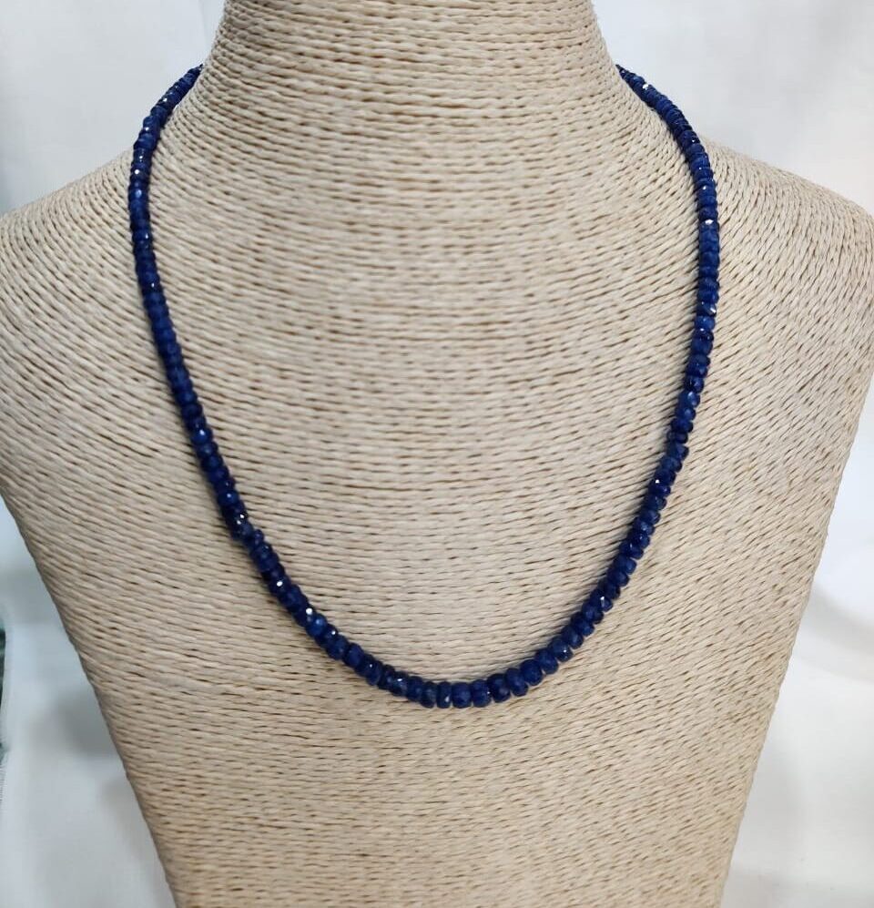 Handcrafted sapphire necklace with faceted blue beads displayed on a neutral woven bust, highlighting Afghan gemstone artistry and emotional symbolism.
