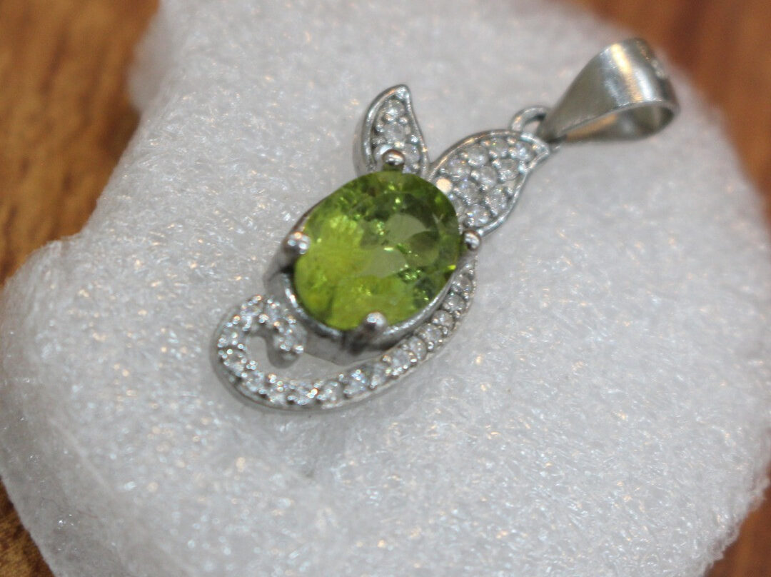 Elegant Peridot pendant set in pure silver resting on a dark velvet surface, showcasing natural green gemstone sparkle and ethical craftsmanship