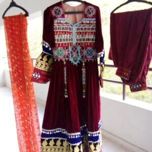 Velvet Kuchi Dress featuring intricate Afghan embroidery, mirrorwork accents, maroon velvet trousers, and a vibrant orange dupatta—styled to reflect traditional elegance and cultural heritage.