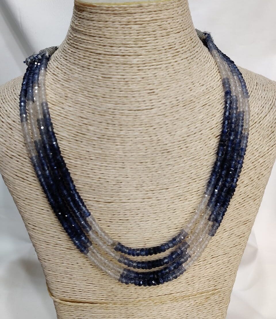 “Multi-strand zircon necklace with gradient beads transitioning from deep blue to clear, elegantly draped on a woven mannequin bust”
